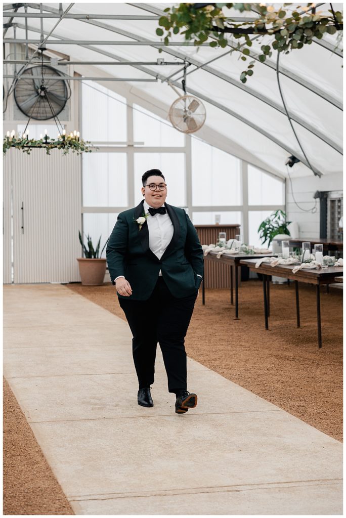 partner wearing suit walks in at modern greenhouse ceremony