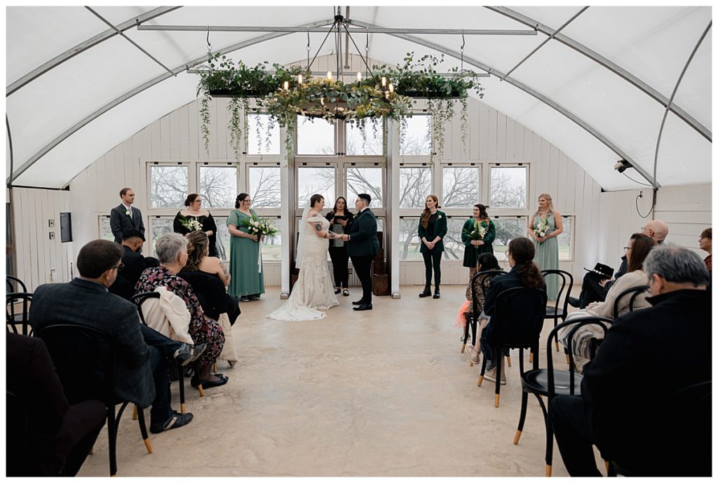 couple holds hands at altar during modern greenhouse ceremony