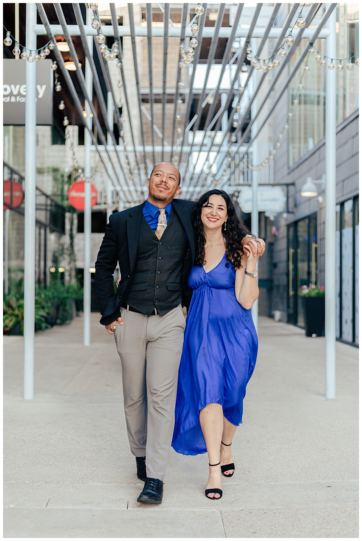 man has arm around woman who is holding his hand while they walk by Ellie Chavez Photography