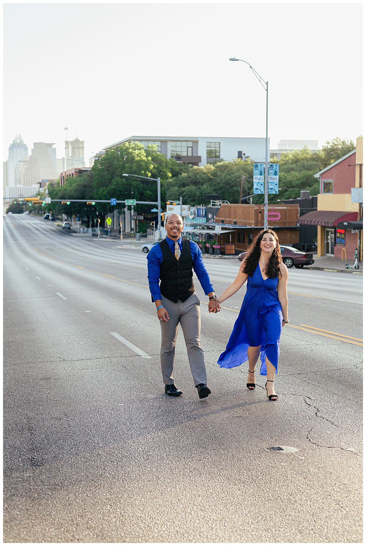 man and woman hold hands walking down middle of street by Ellie Chavez Photography