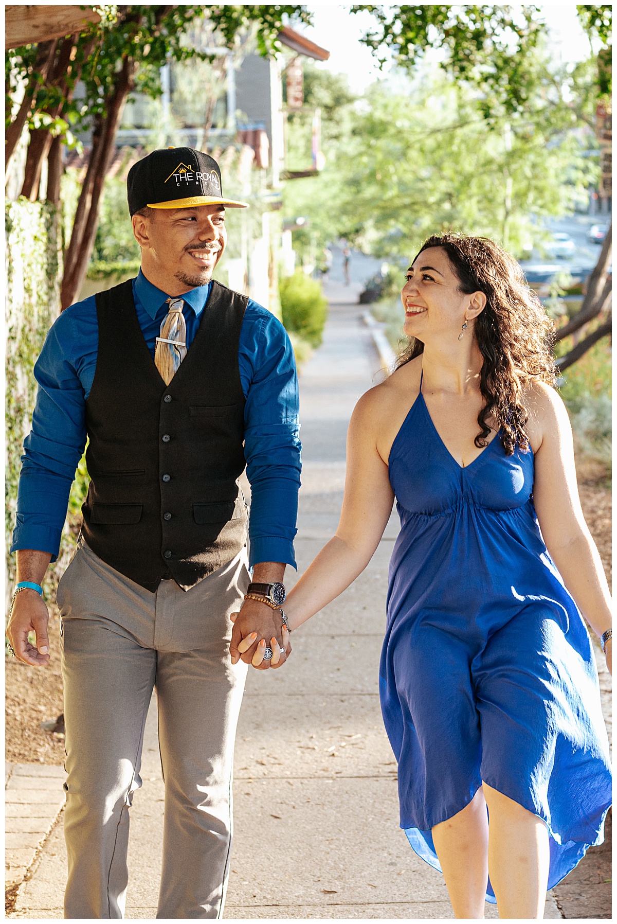 man and woman walk down sidewalk holding hands and smiling by Ellie Chavez Photography