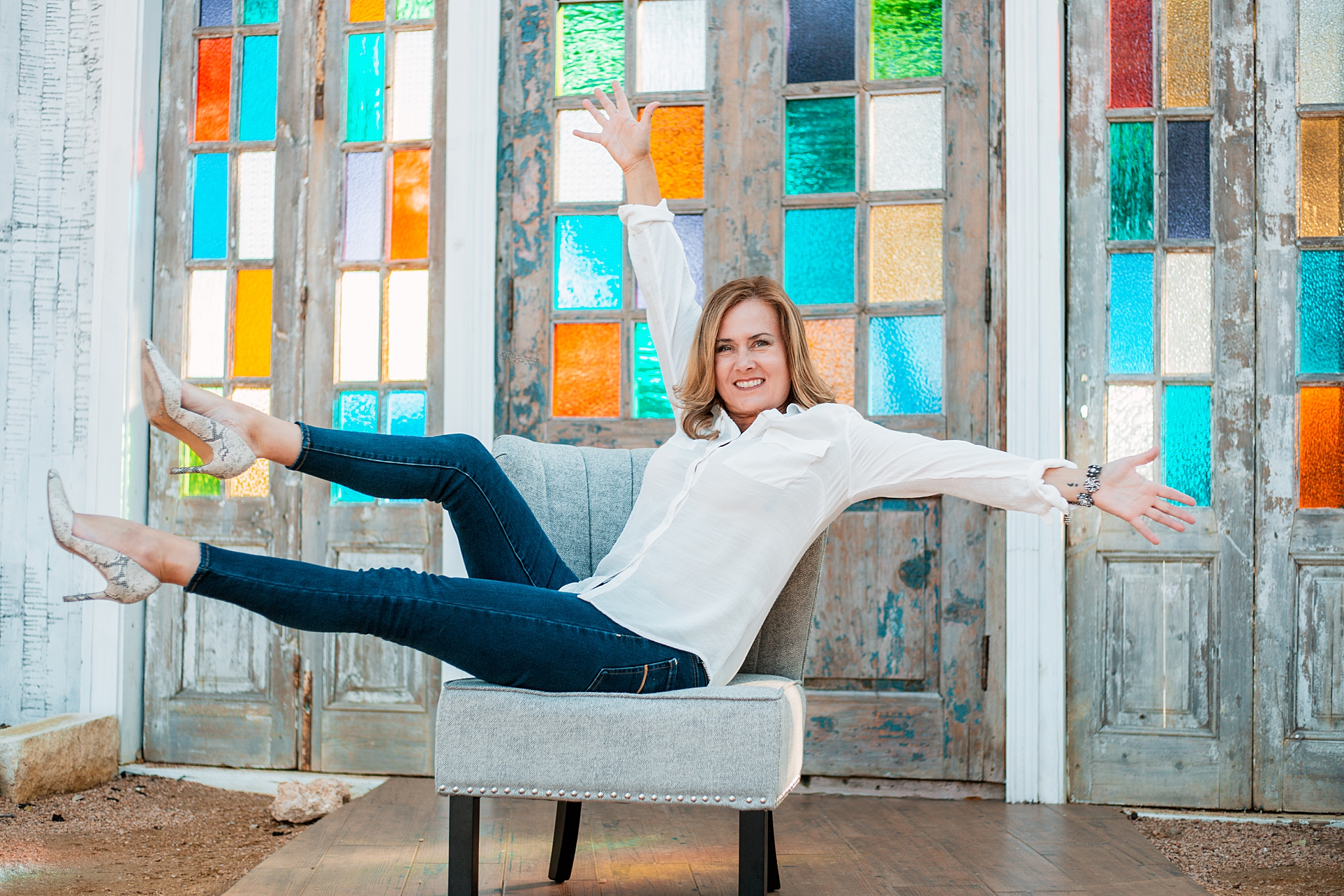 woman leans back in chair with arms and legs outstretched for brand photo shoot 