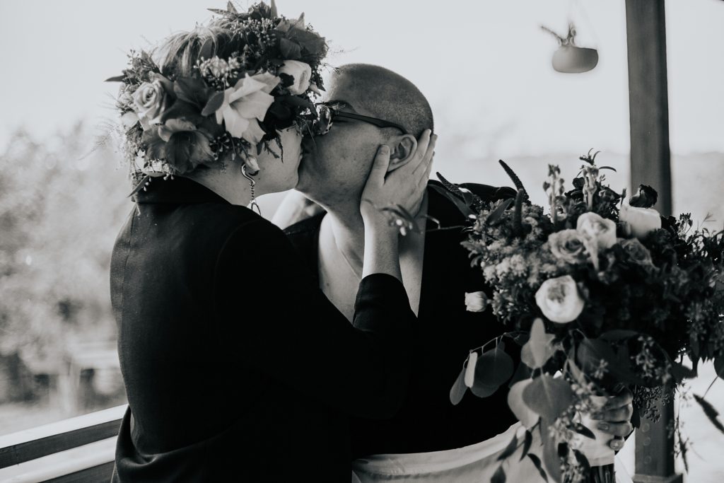 couple kisses while holding bouquet by Austin Wedding Photographer