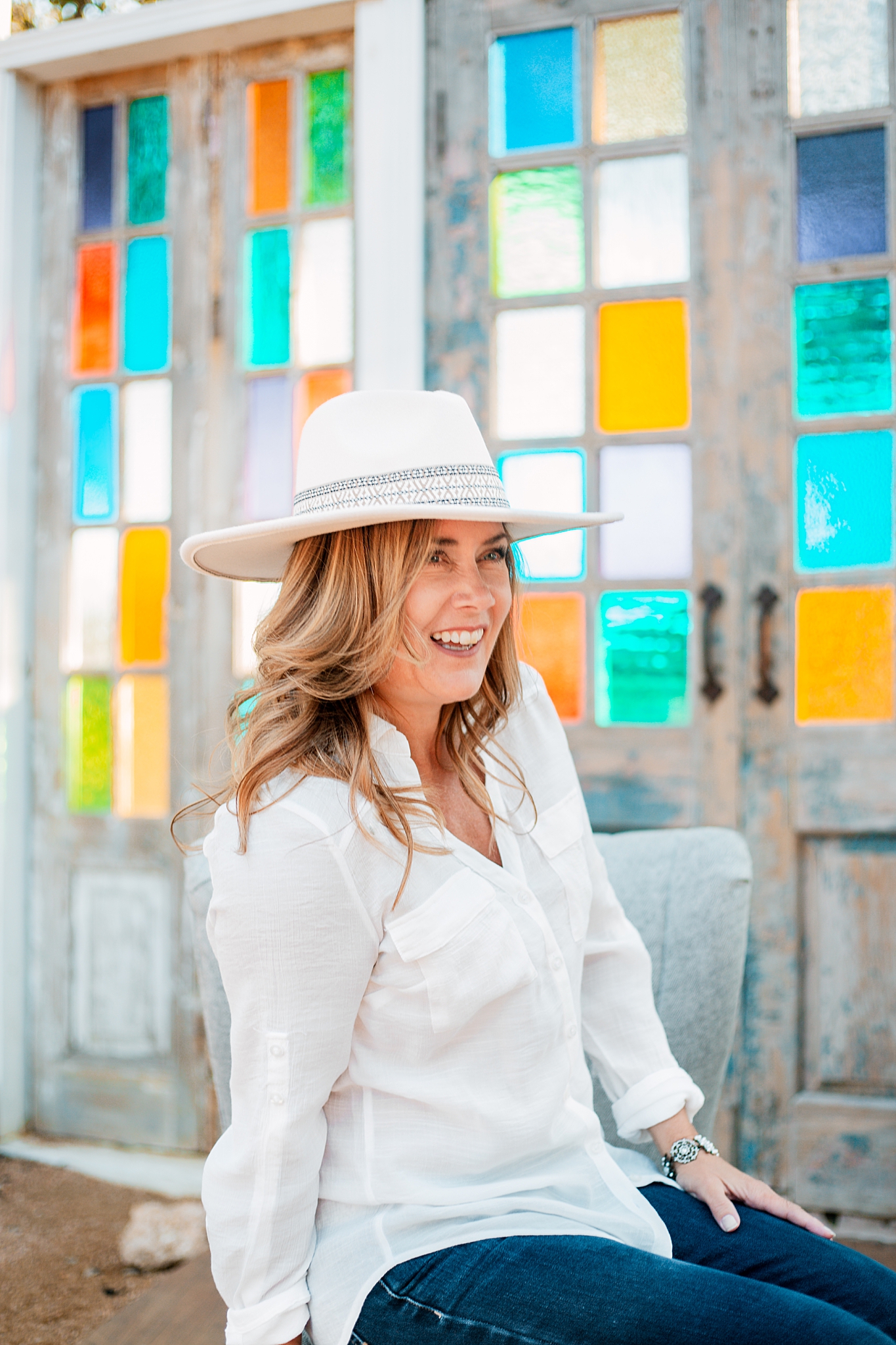 woman smiles while wearing cowboy hat for brand photo shoot 