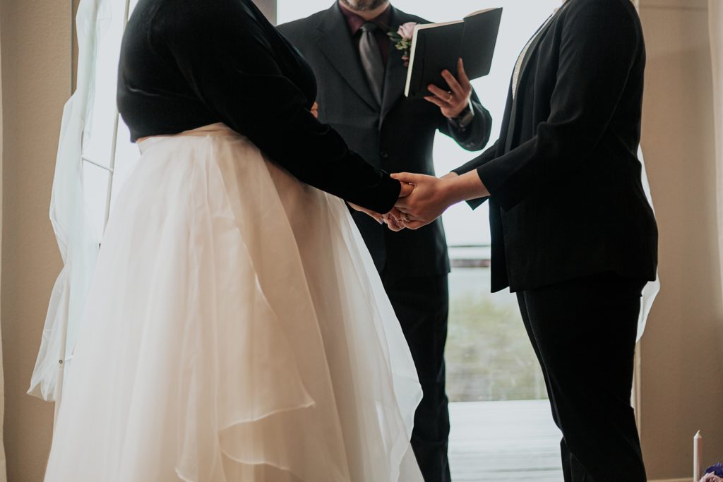 couple holds hands during ceremony by Ellie Chavez Photography 
