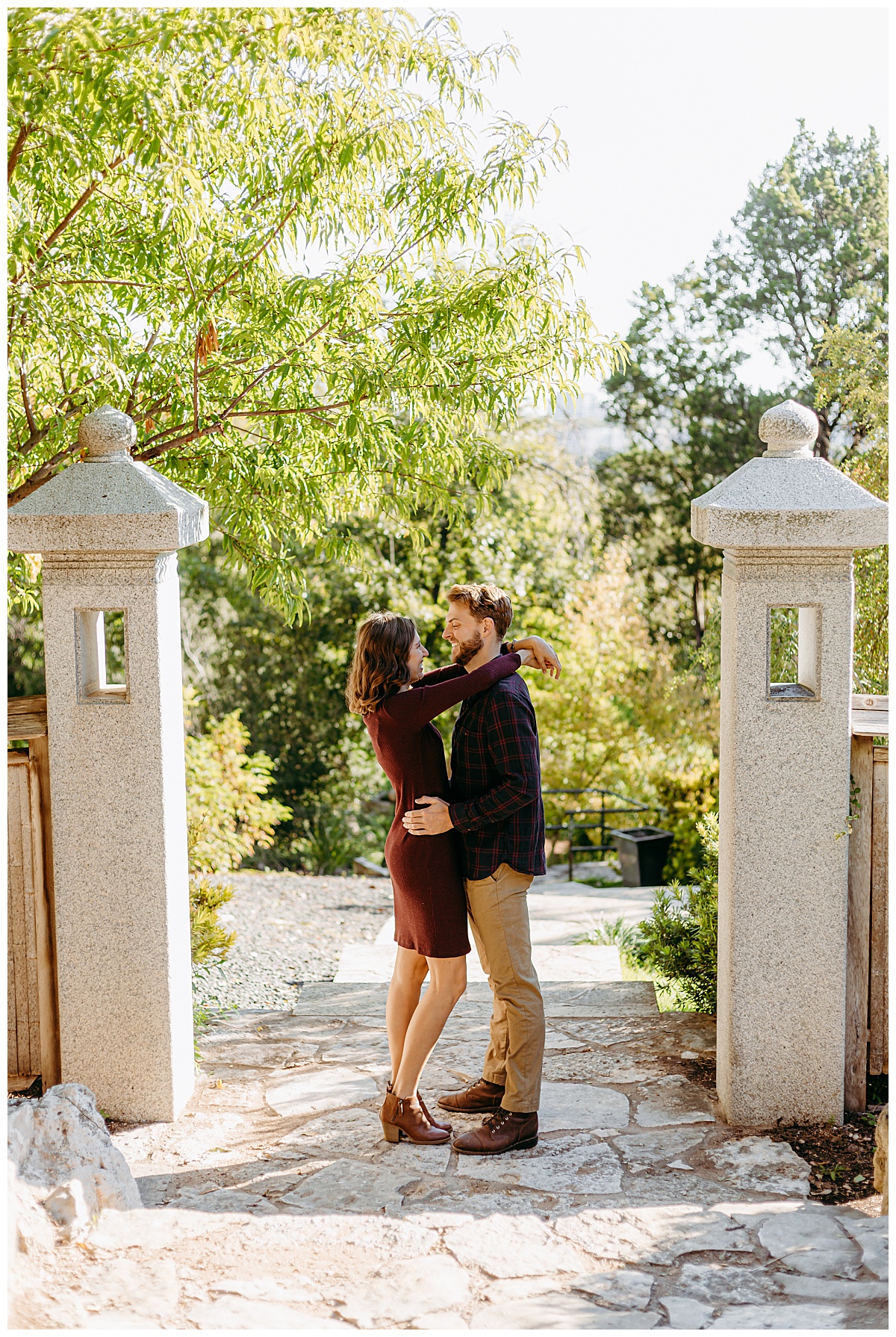 Fiances stand with arms around each other at garden engagement session