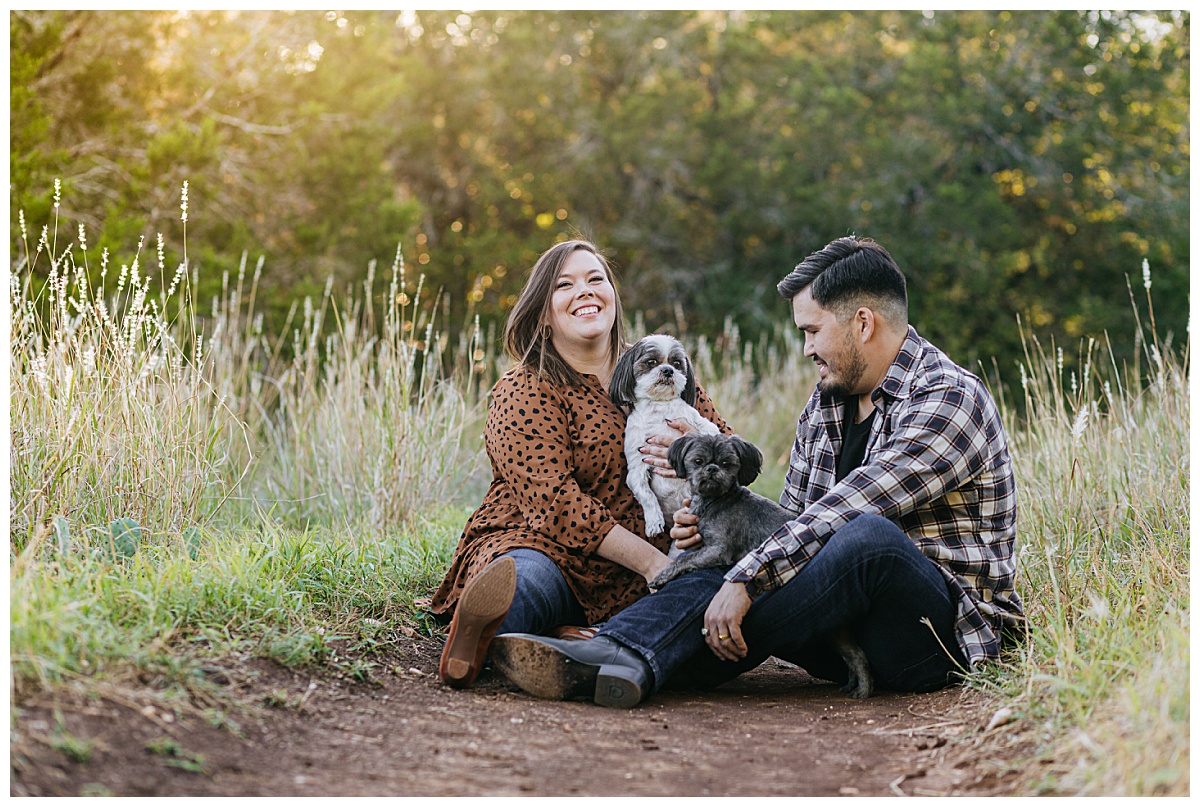 Man and woman sit on trail with dogs for Austin wedding photographer