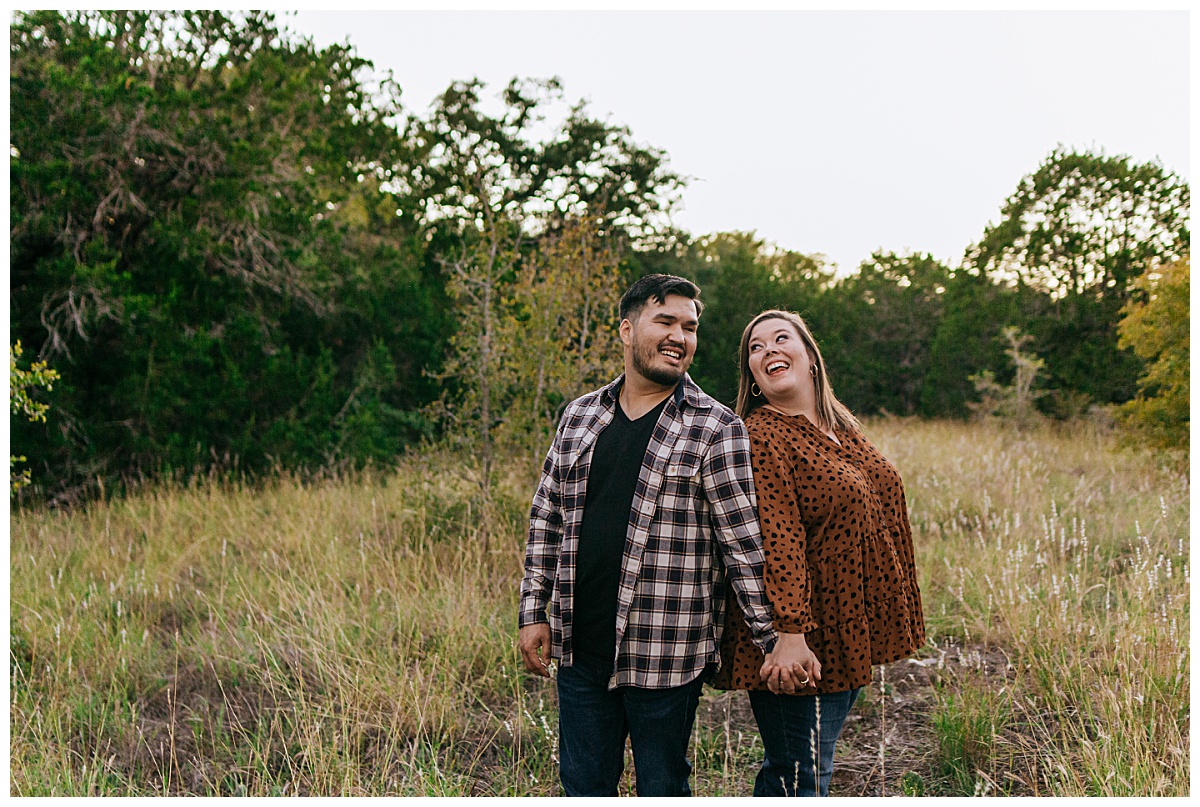 couple smiles at each other in field at St. Edwards Park engagement session