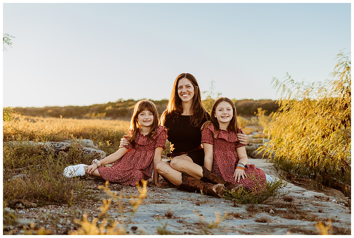 woman and girls sit together on rock by Austin portrait photographer