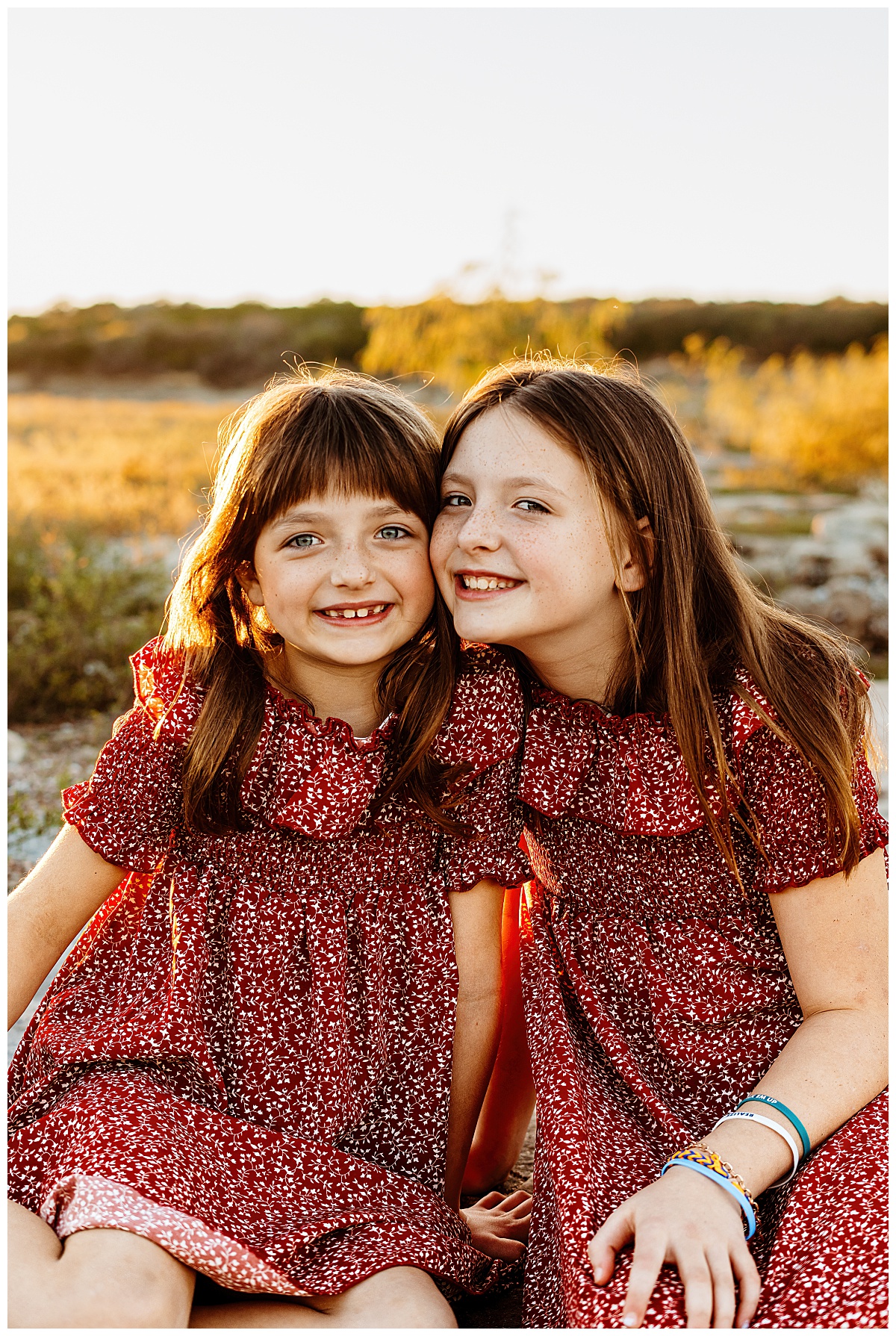 sisters lean together and grin by Austin portrait photographer