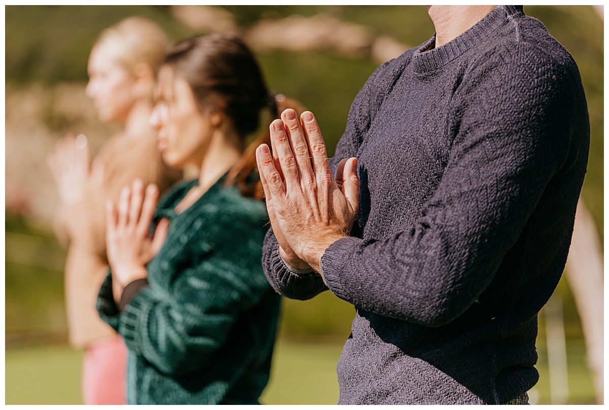 man holds hands in praying pose in front of his heart by Ellie Chavez Photography