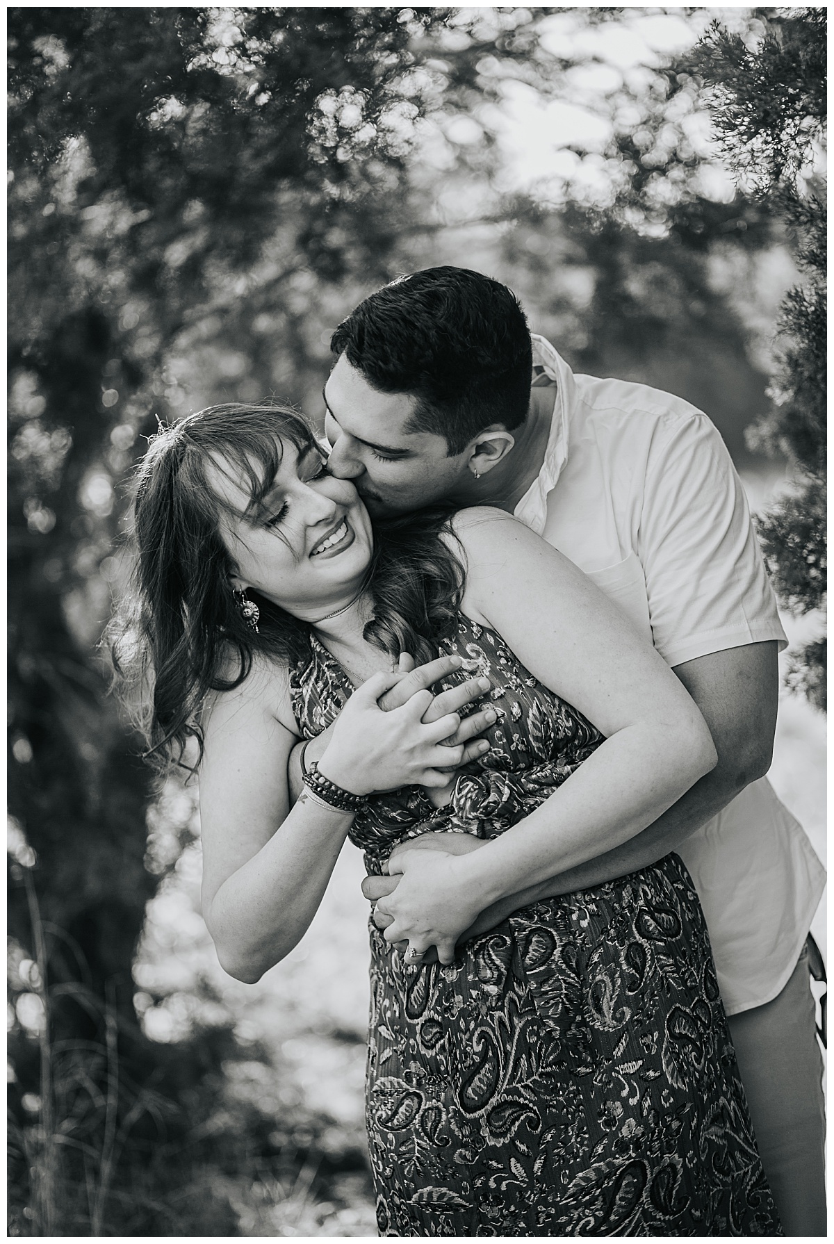 guy hugs girl and kisses her as she smiles by Ellie Chavez Photography