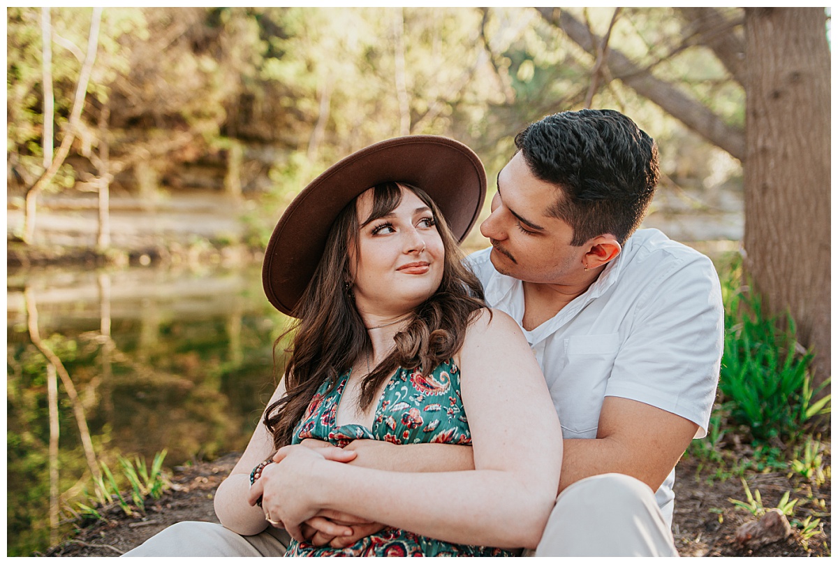 girl sits in guy's lap and looks back at him by Ellie Chavez Photography