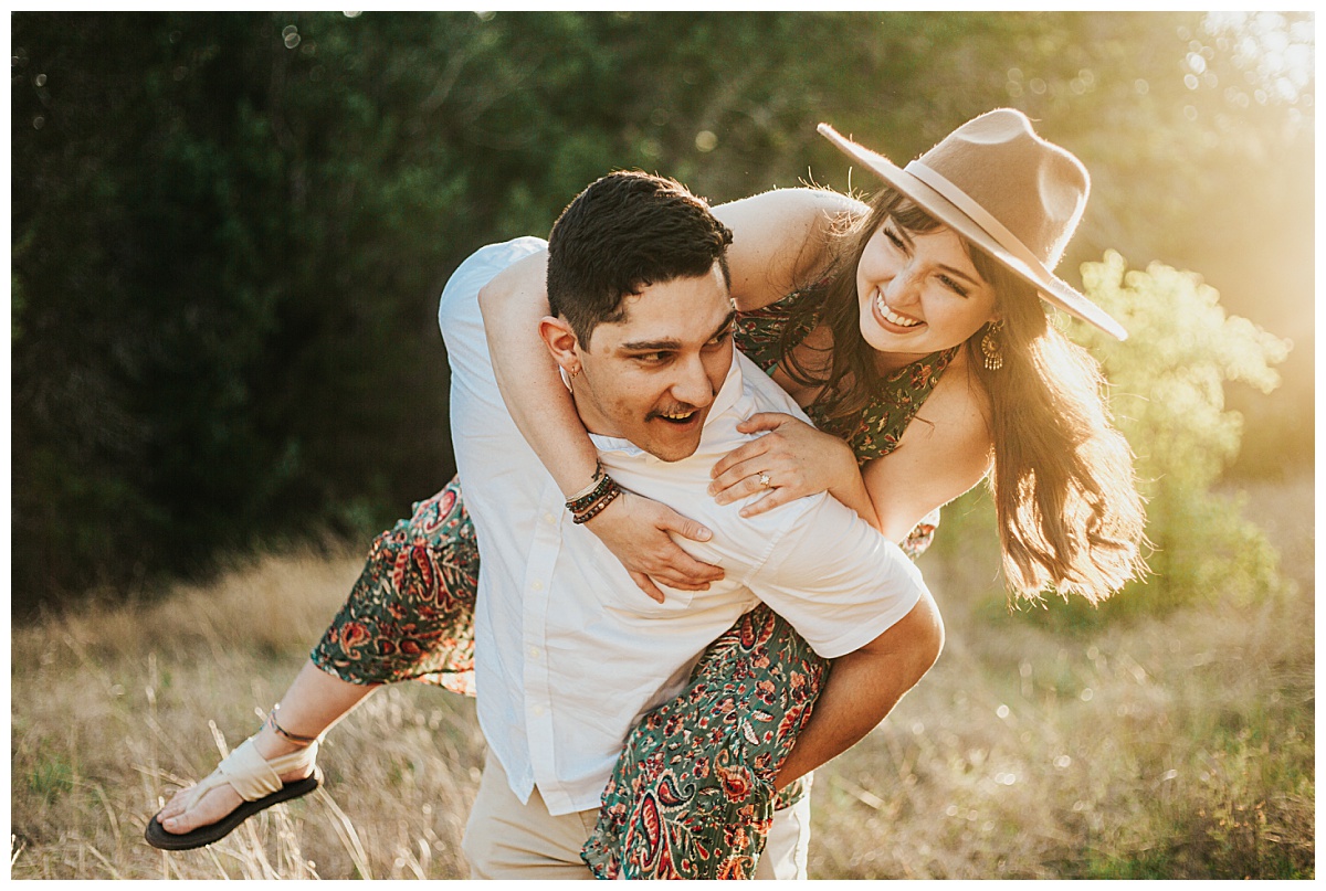 man carries woman on his back as they laugh by Austin wedding photographer