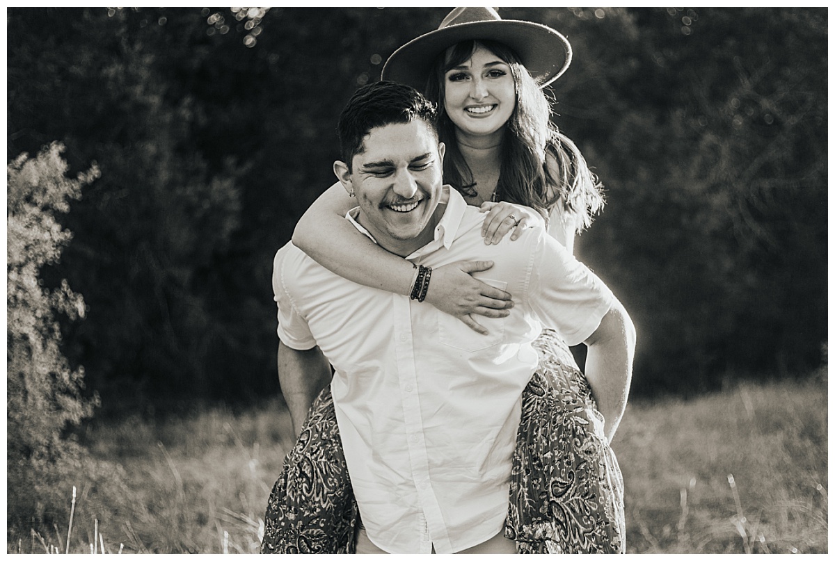 couple smiles and laughs together in field by Ellie Chavez Photography